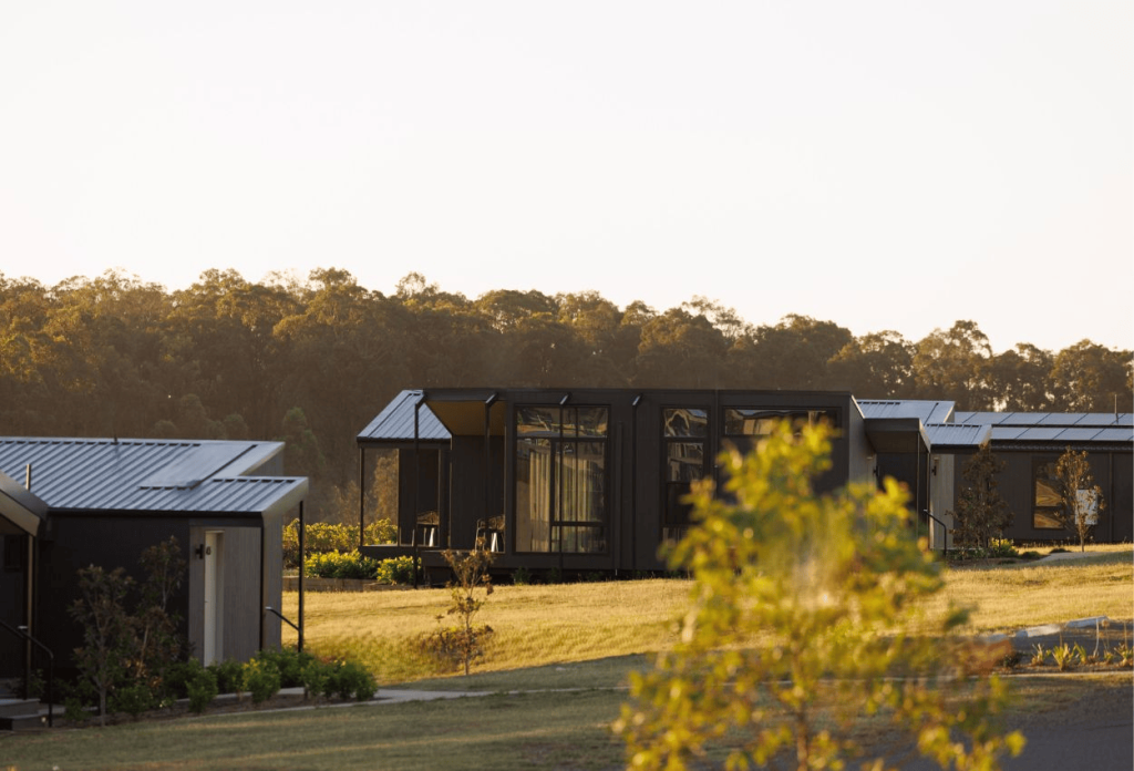 Dark timber cabins at The Lane Retreat in late afternoon light